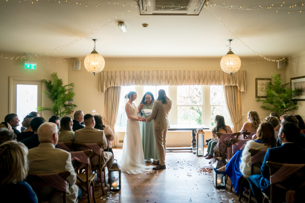A group of people standing in a room with chairs and a window, enjoying a gathering at the Shireburn Arms in Lancashire. Image by Andy Wade Photography.