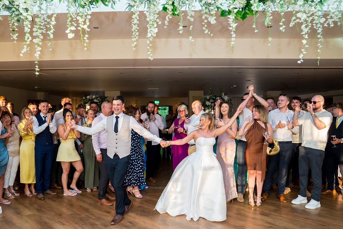 Bride and groom dancing with joyful wedding guests.