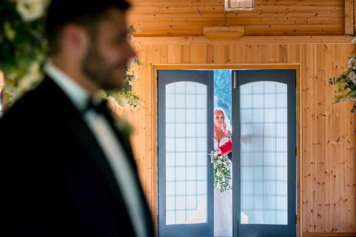 Bride entering chapel, groom waiting inside.