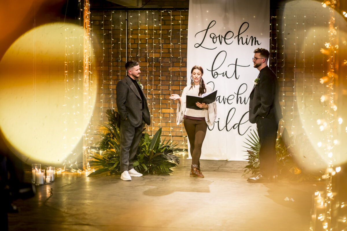 Three people at indoor event, decorative lights.