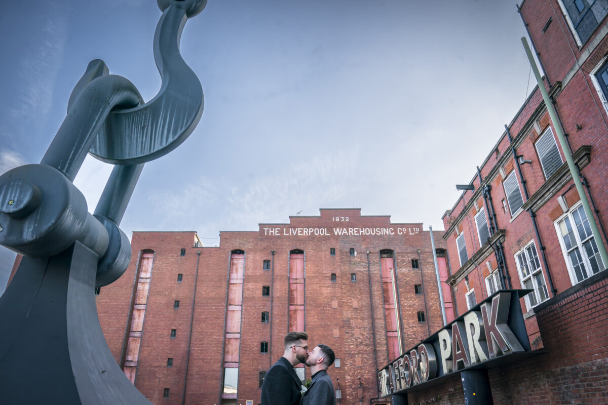 Couple kissing under large metal sculpture in Liverpool.