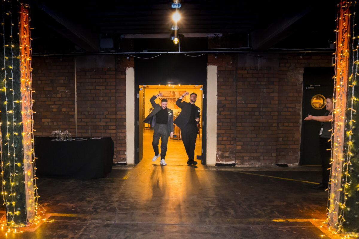 Two men walking into a decorated brick venue