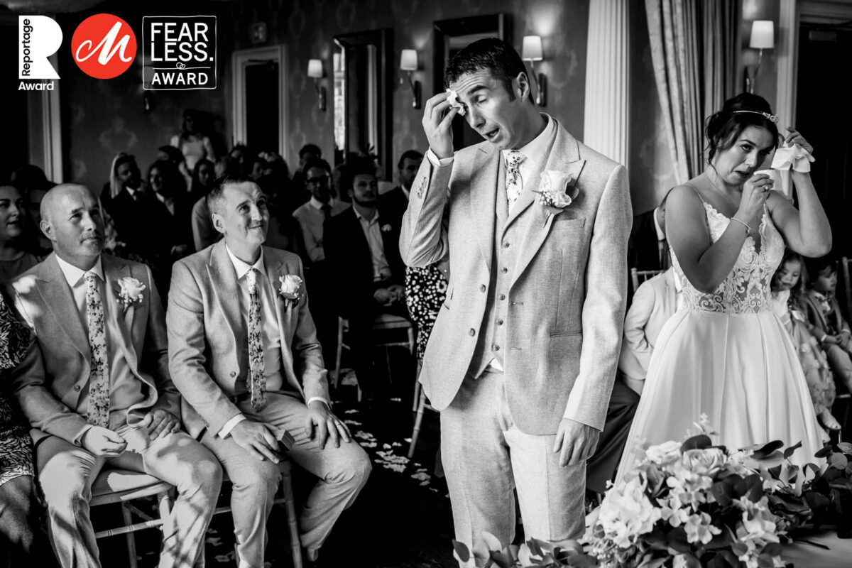 Bride and groom wiping tears during wedding ceremony.