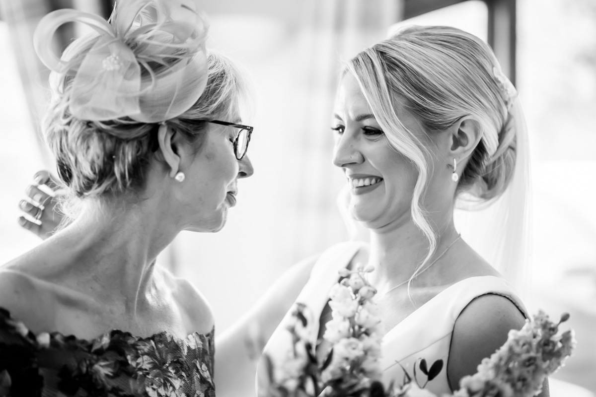 Bride and older woman smiling, wedding day.