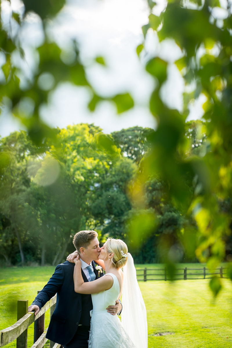 Bride and groom kissing in a garden.
