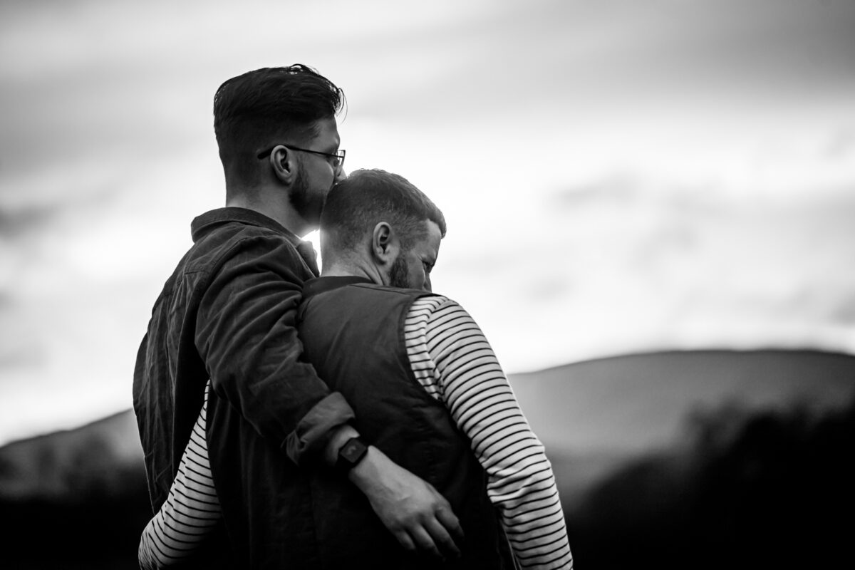Couple embracing outdoors, monochrome landscape background.