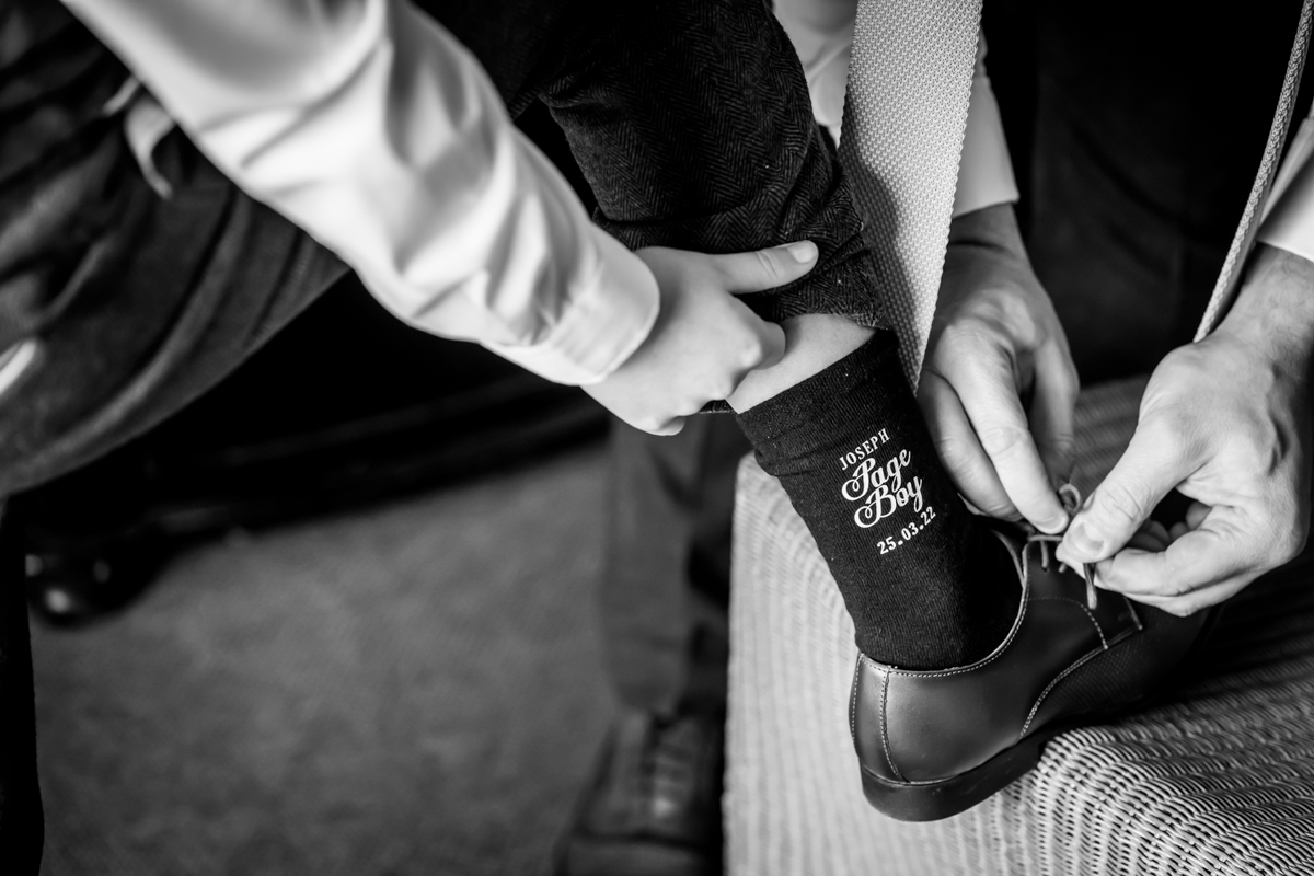 Groom adjusts page boy's shoe at wedding