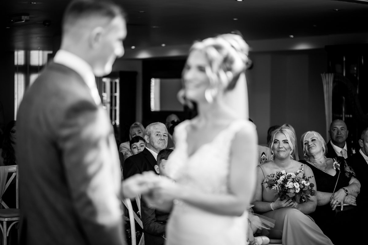 Bride and groom at wedding ceremony, guests smiling.