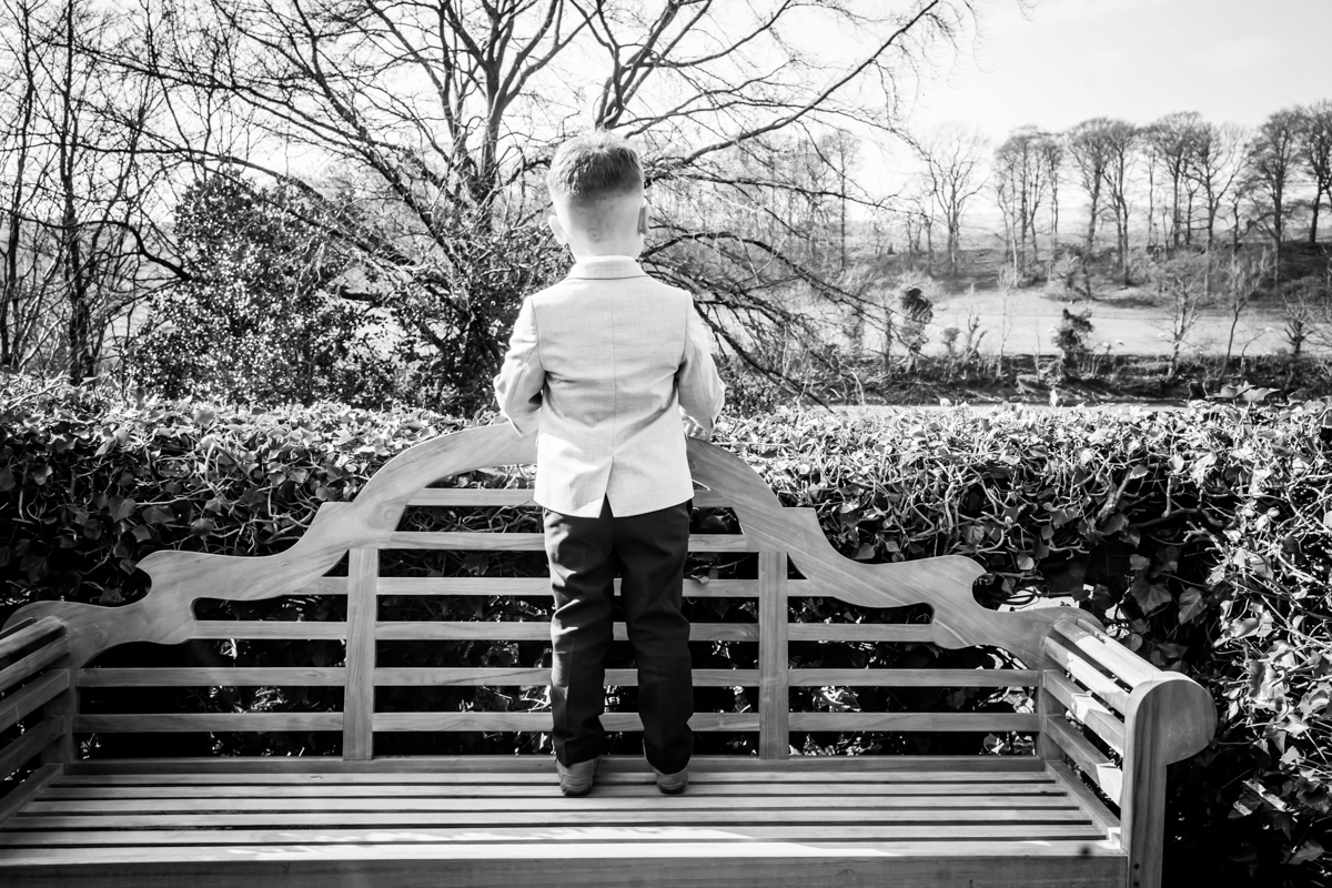 Child standing on bench, overlooking countryside landscape.