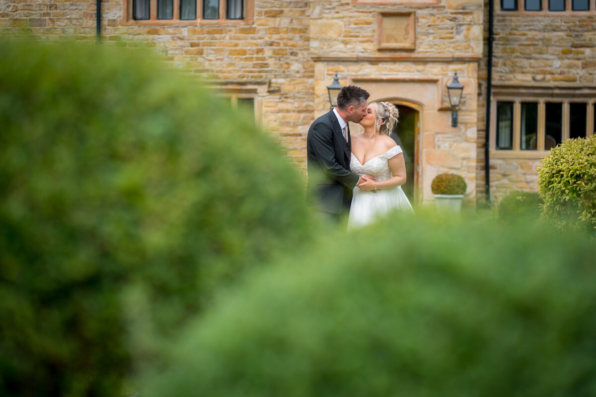 Bride and groom kissing in garden