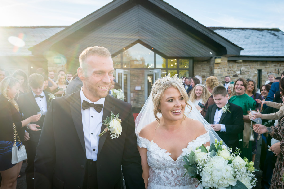 Happy couple at outdoor wedding ceremony with guests.