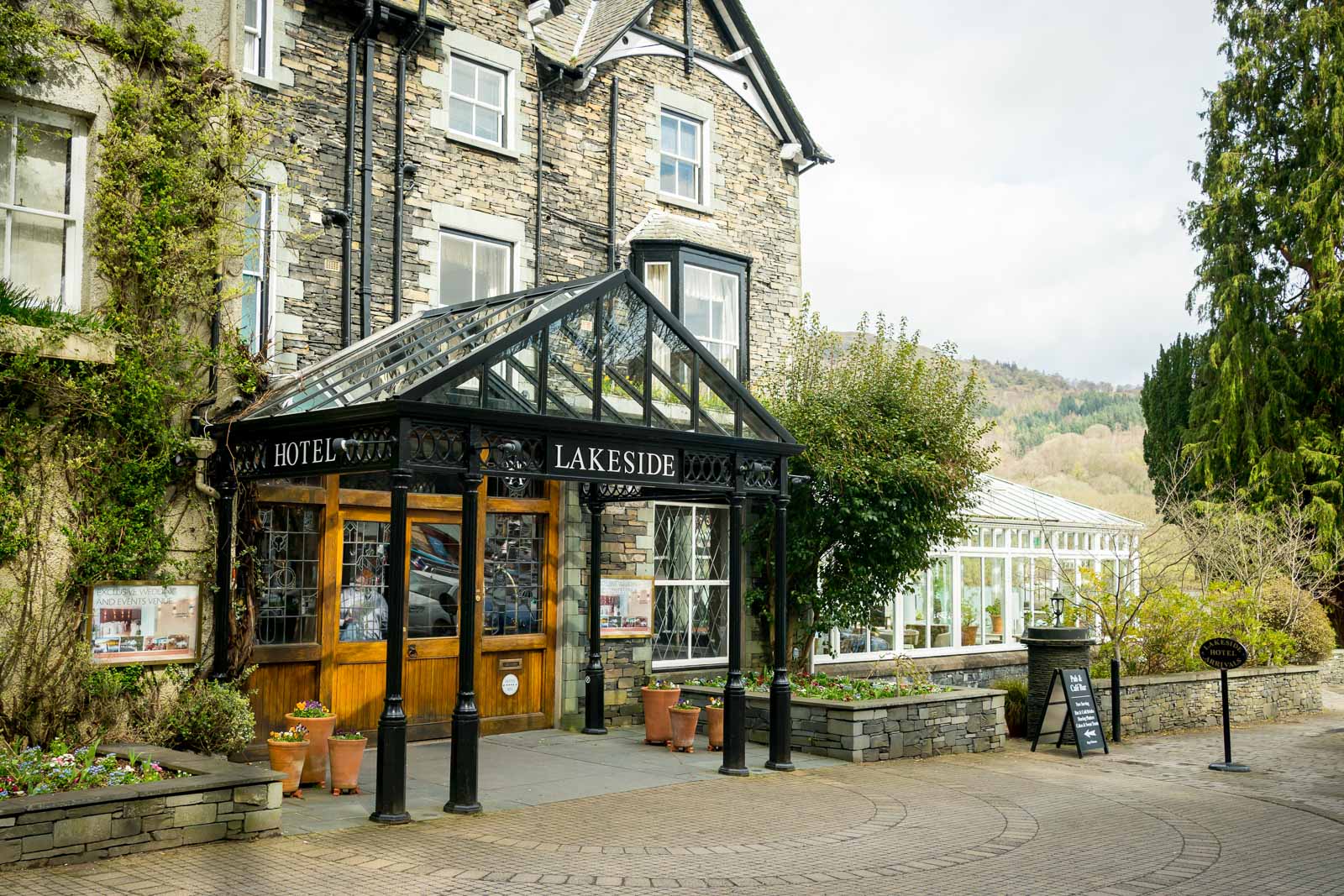 Lakeside Hotel entrance with stone facade and plants.