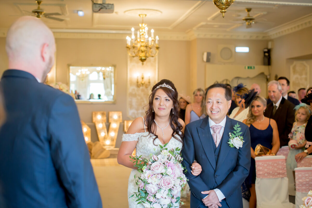 Bride walks down aisle with father at wedding.