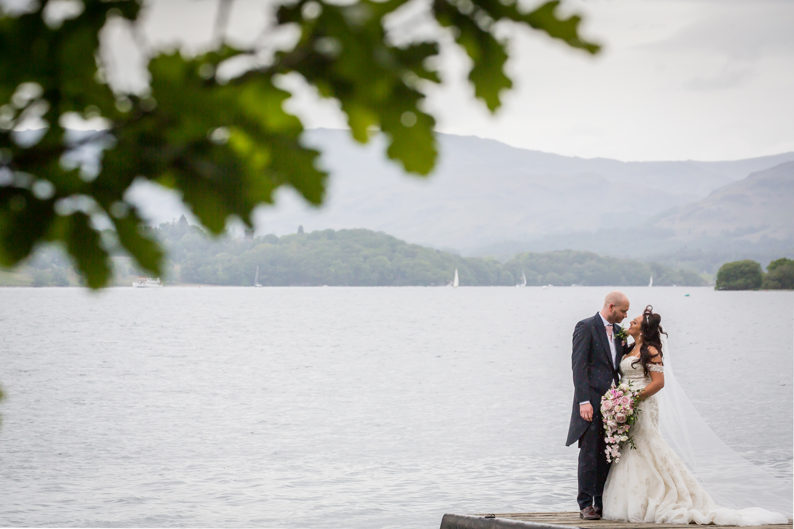 Wedding couple embraces by scenic lakeside.