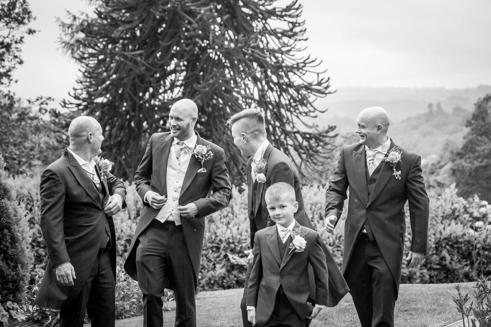 Group of groomsmen and boy in suits outside.