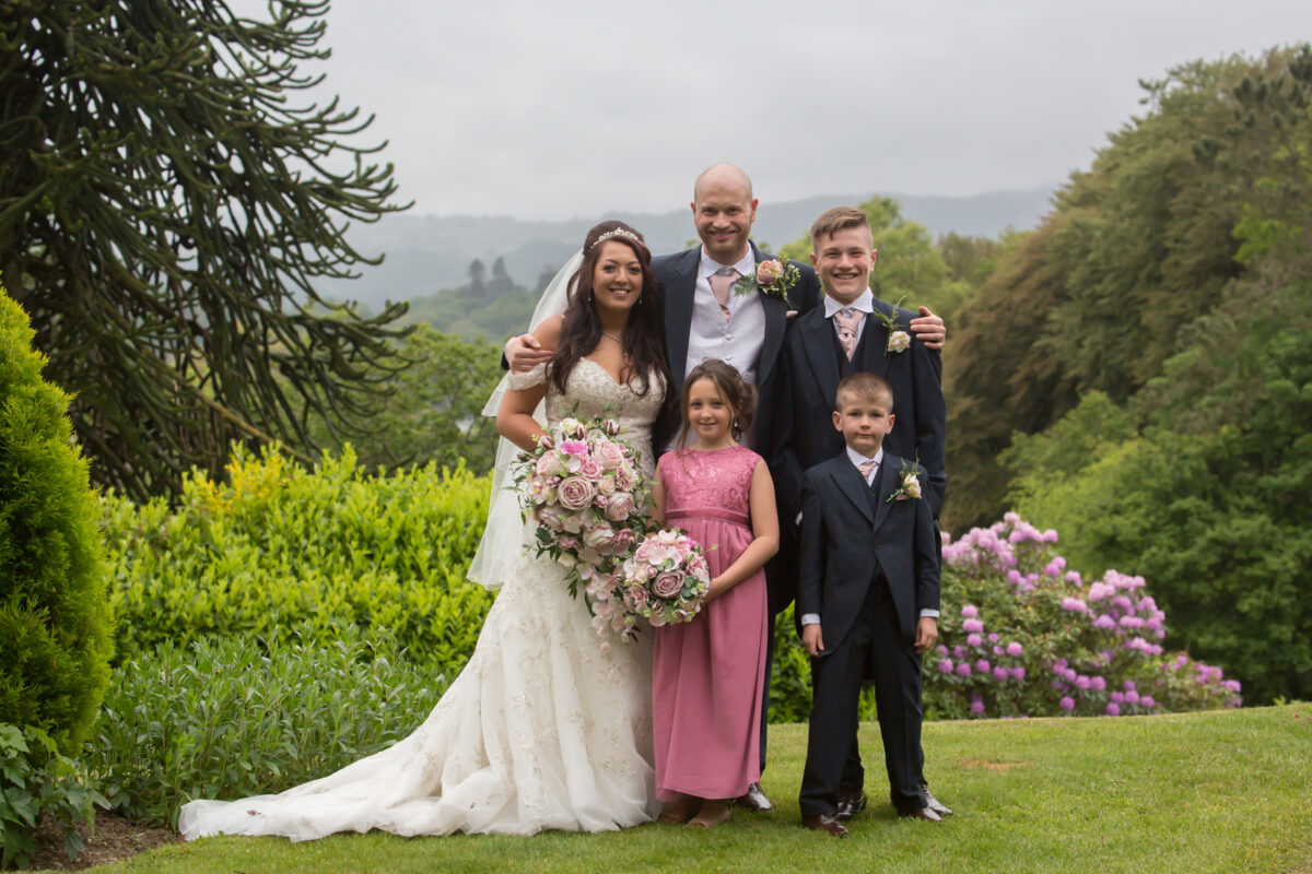 Family in wedding attire, posing outdoors.