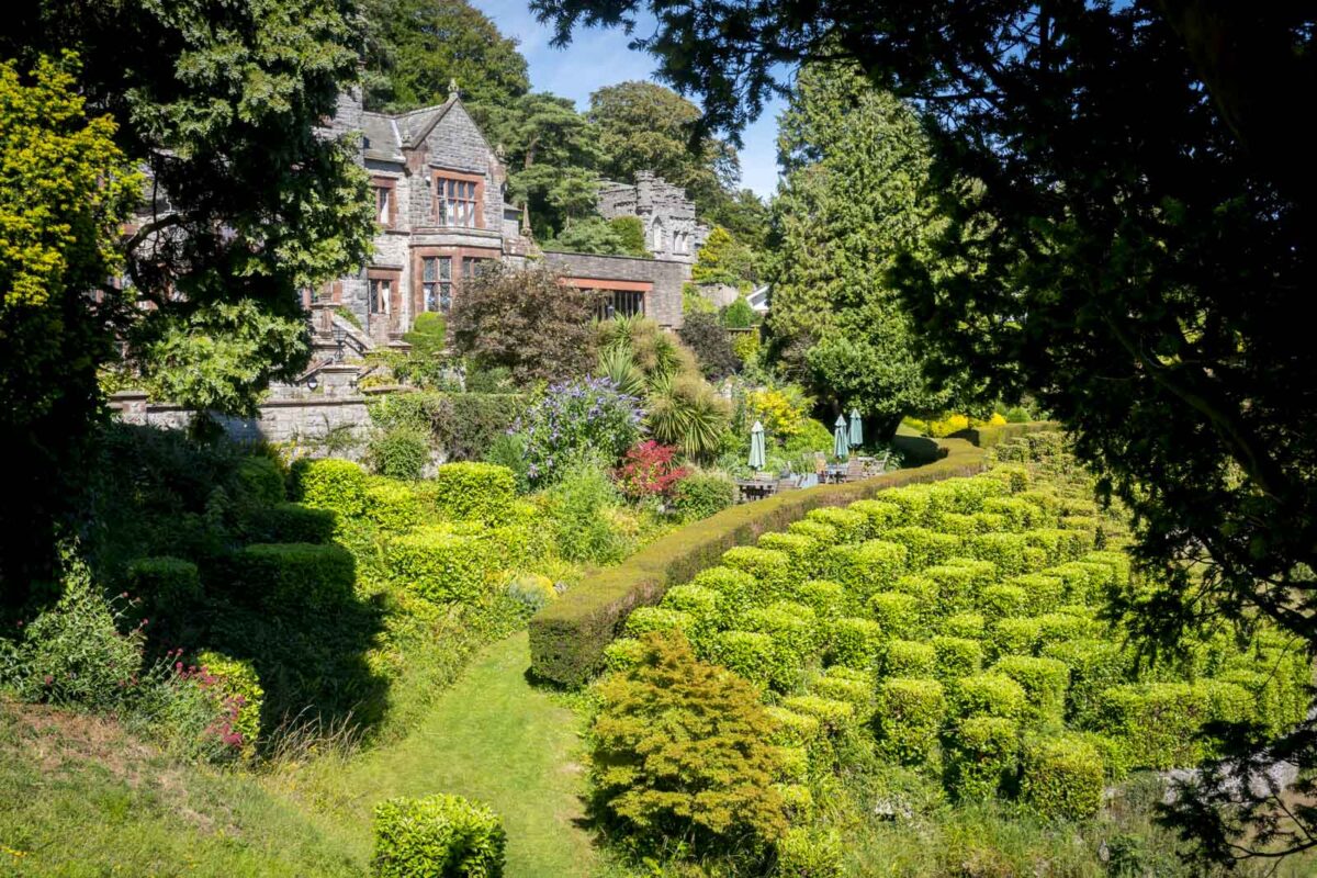Lush garden with stone house in the background.