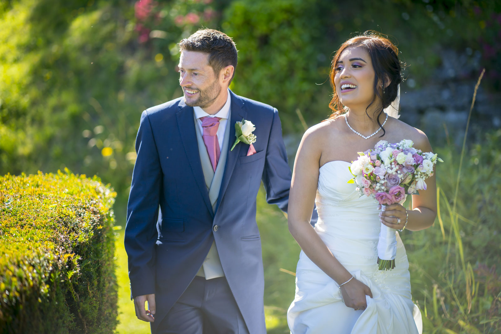 Bride and groom laughing in sunny garden