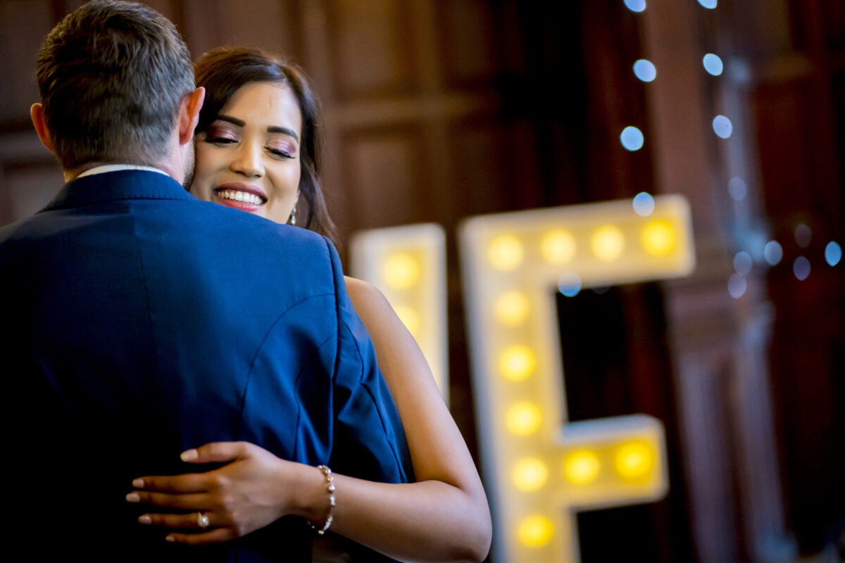 Couple dancing at wedding reception with marquee lights.
