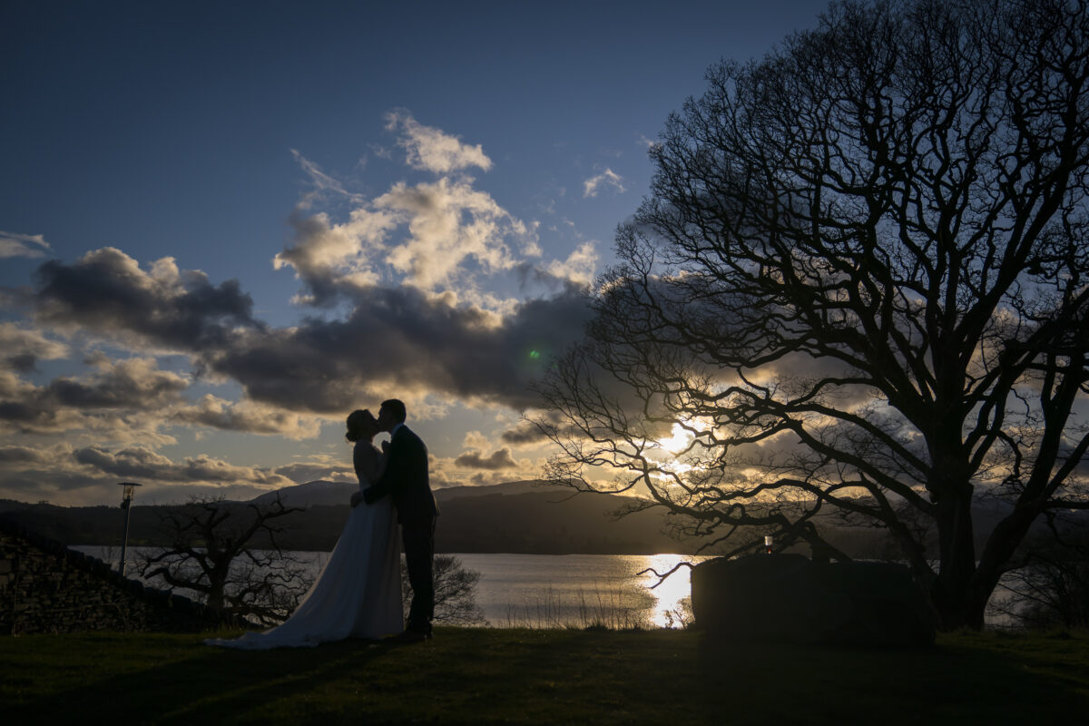 Couple kissing at sunset by a lake.