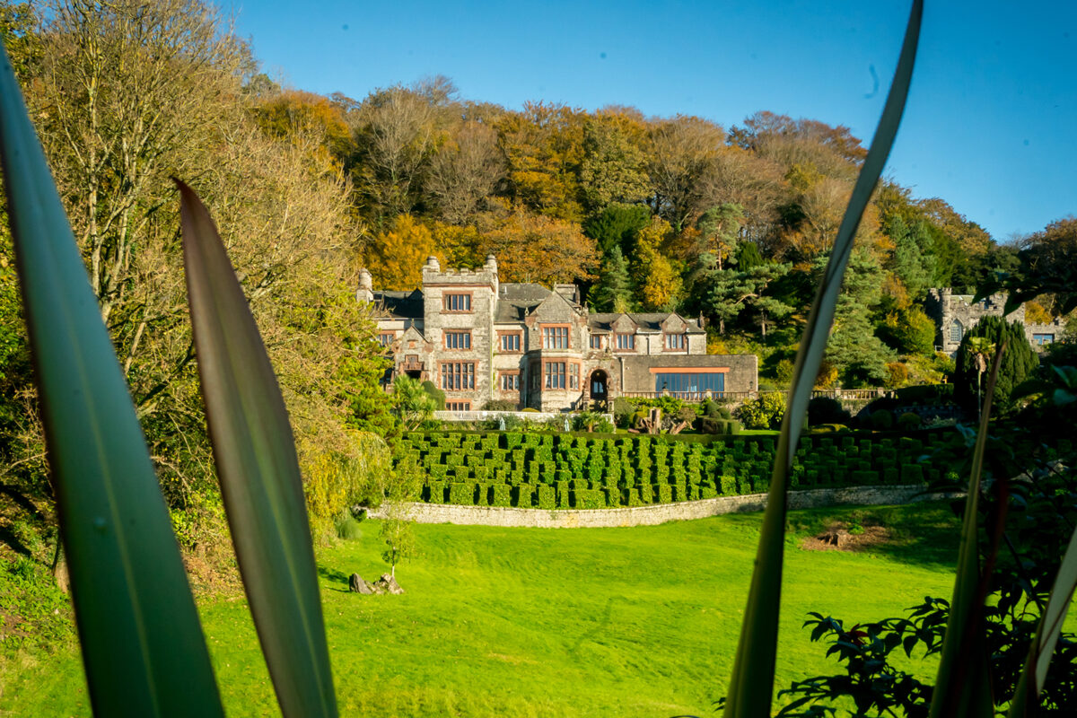 Historic manor house with surrounding gardens and trees.