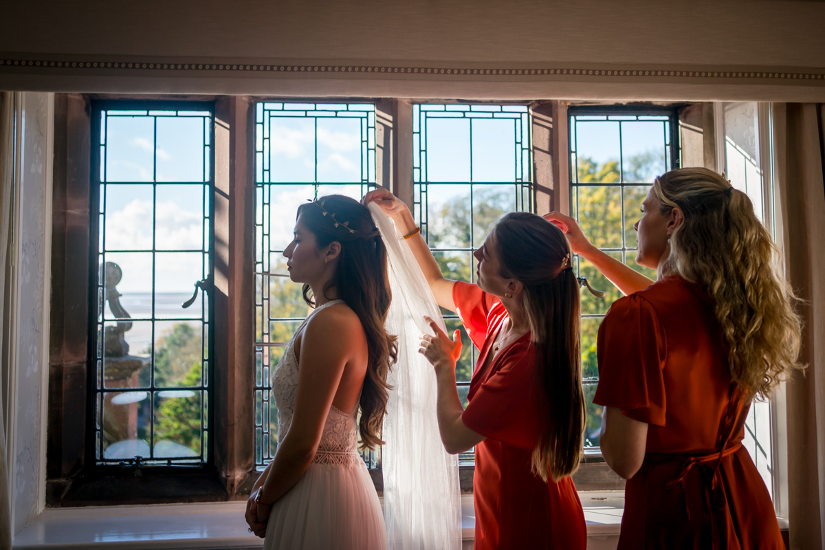 Bridesmaids adjust bride's veil before ceremony