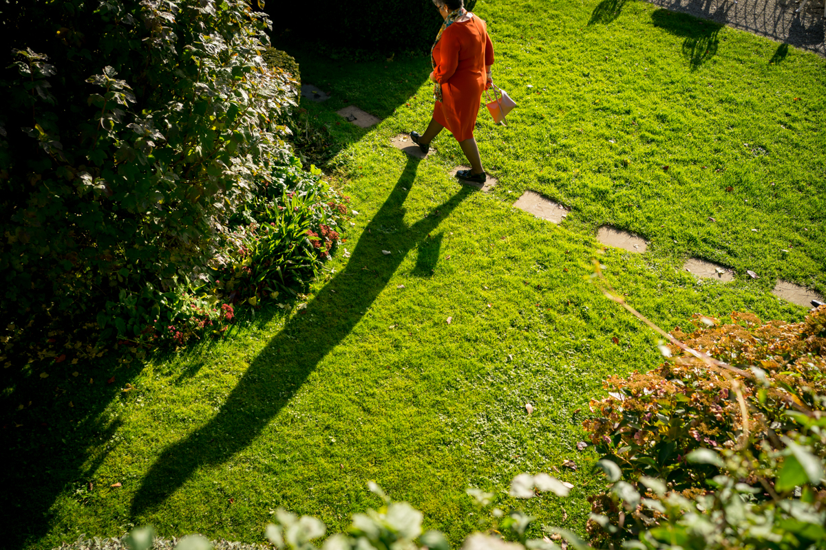 Person in orange coat walking on green lawn