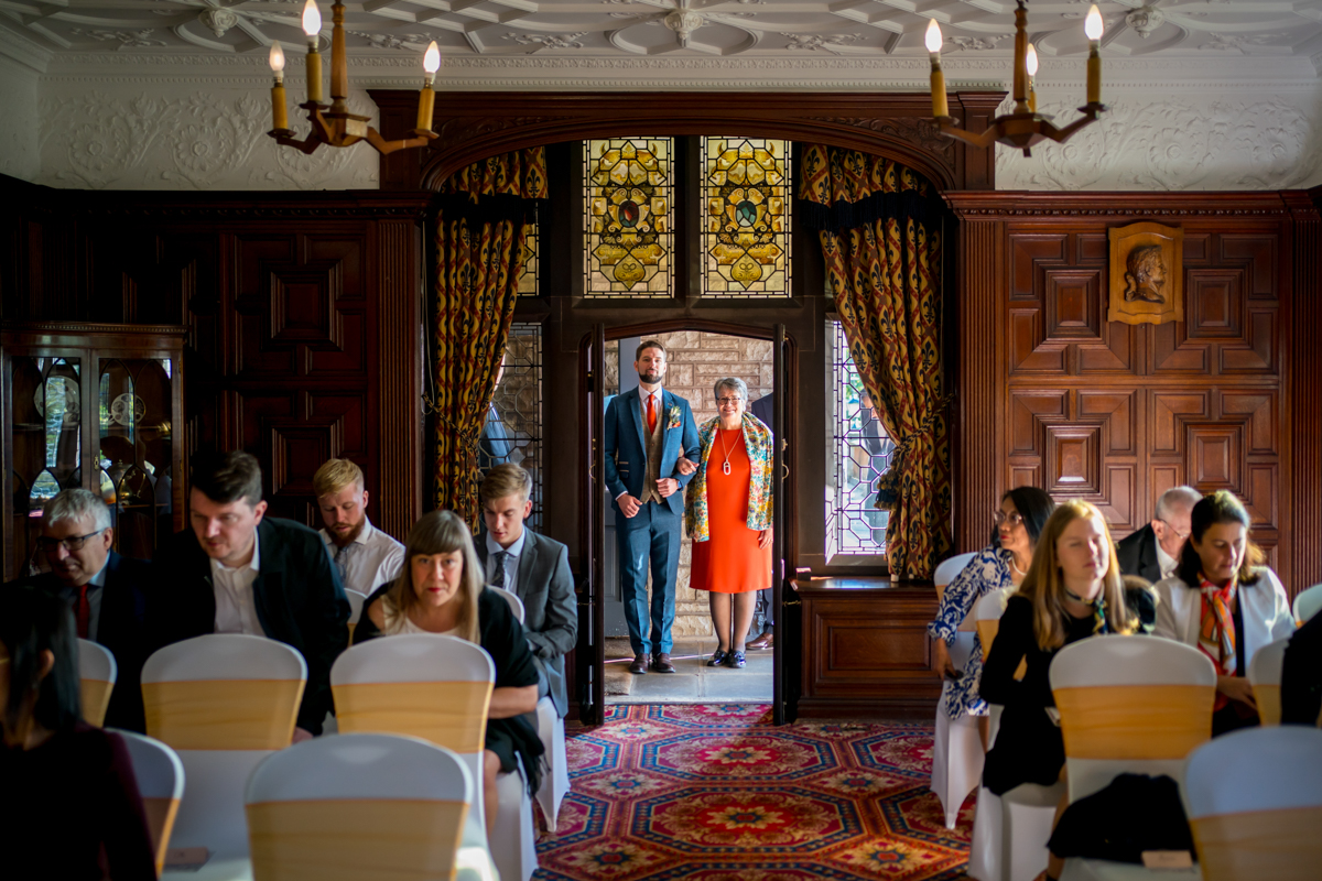 Wedding guests seated in ornate room.
