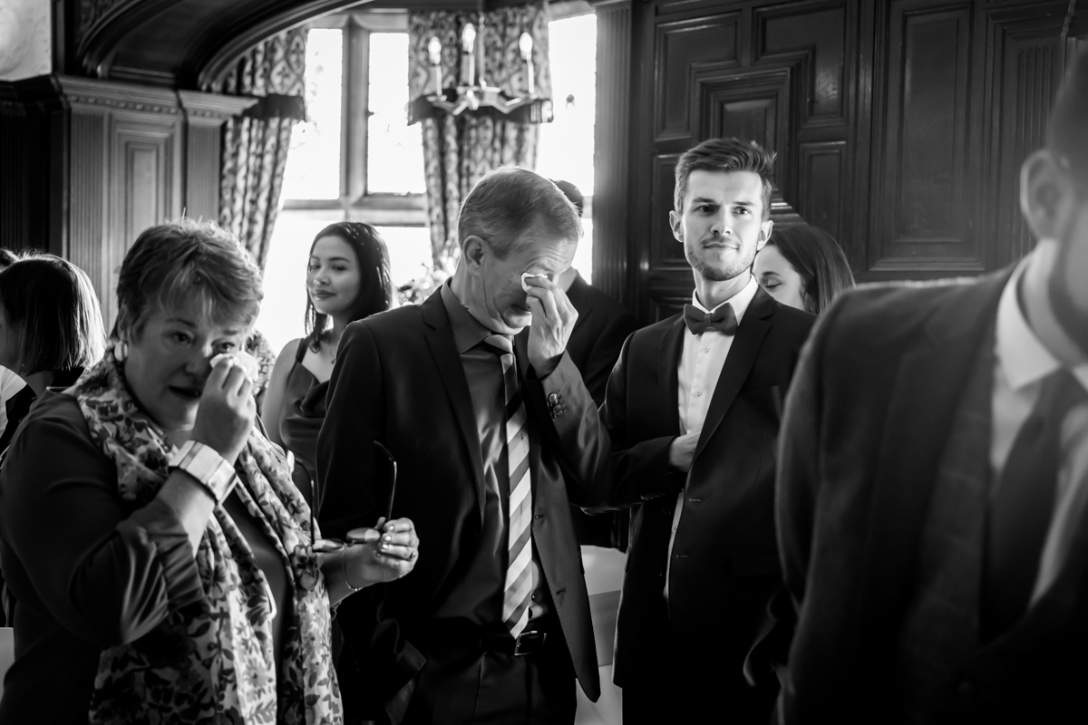 Guests in formal wear, some appearing emotional.
