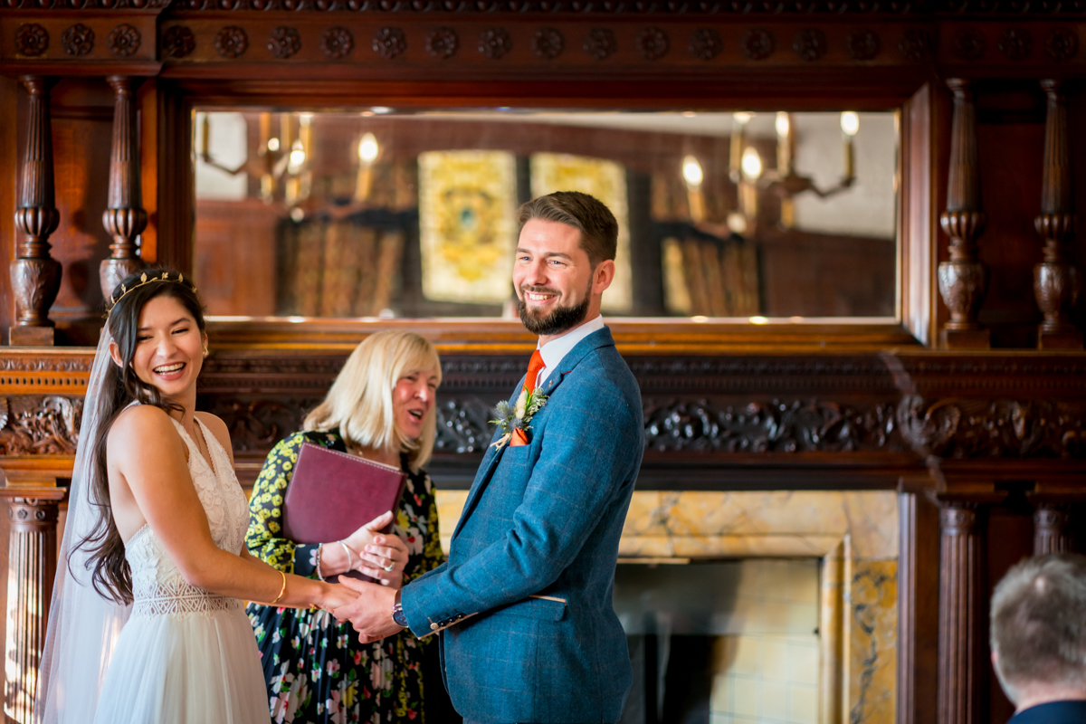 Couple getting married with officiant in ornate room.