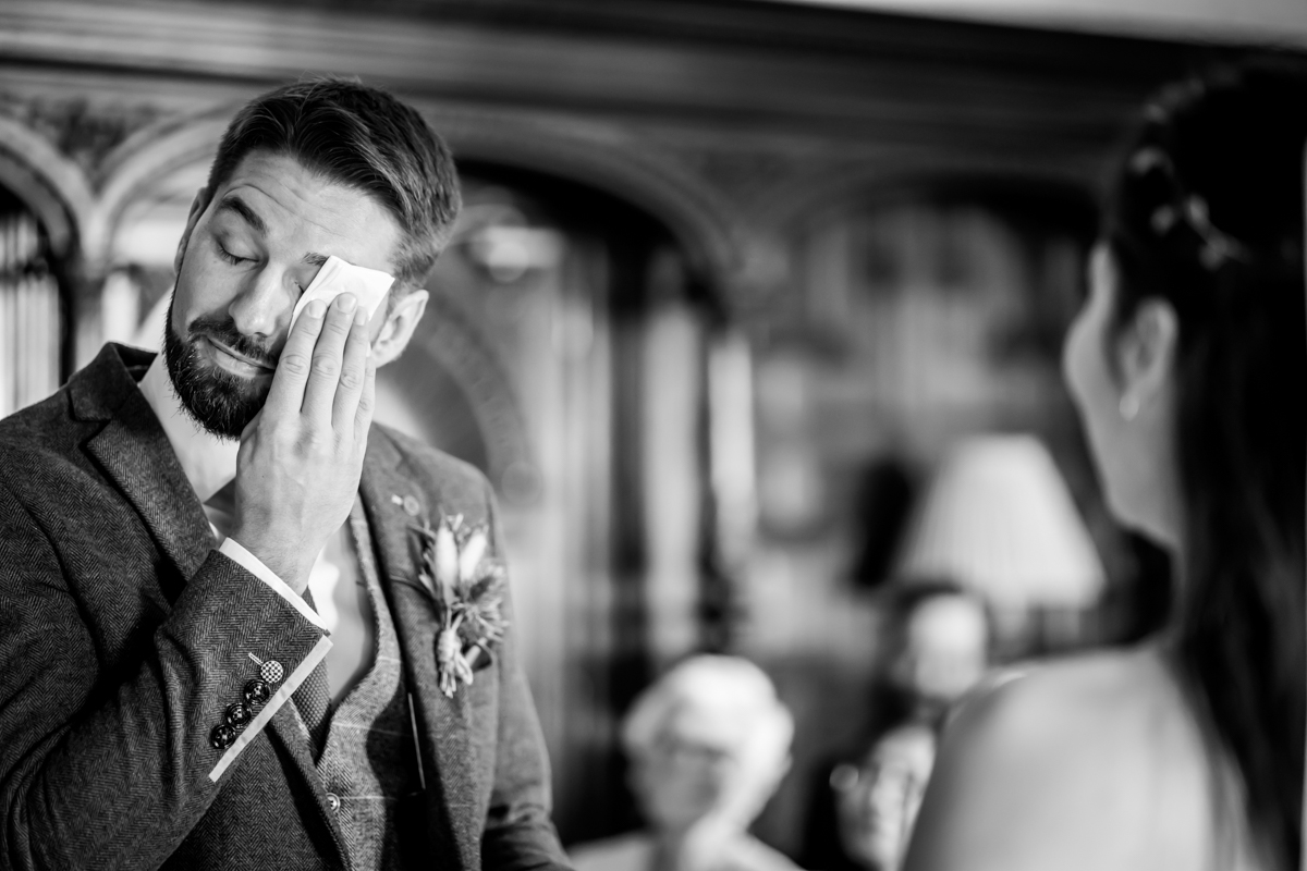 Groom wipes tears during emotional wedding ceremony.
