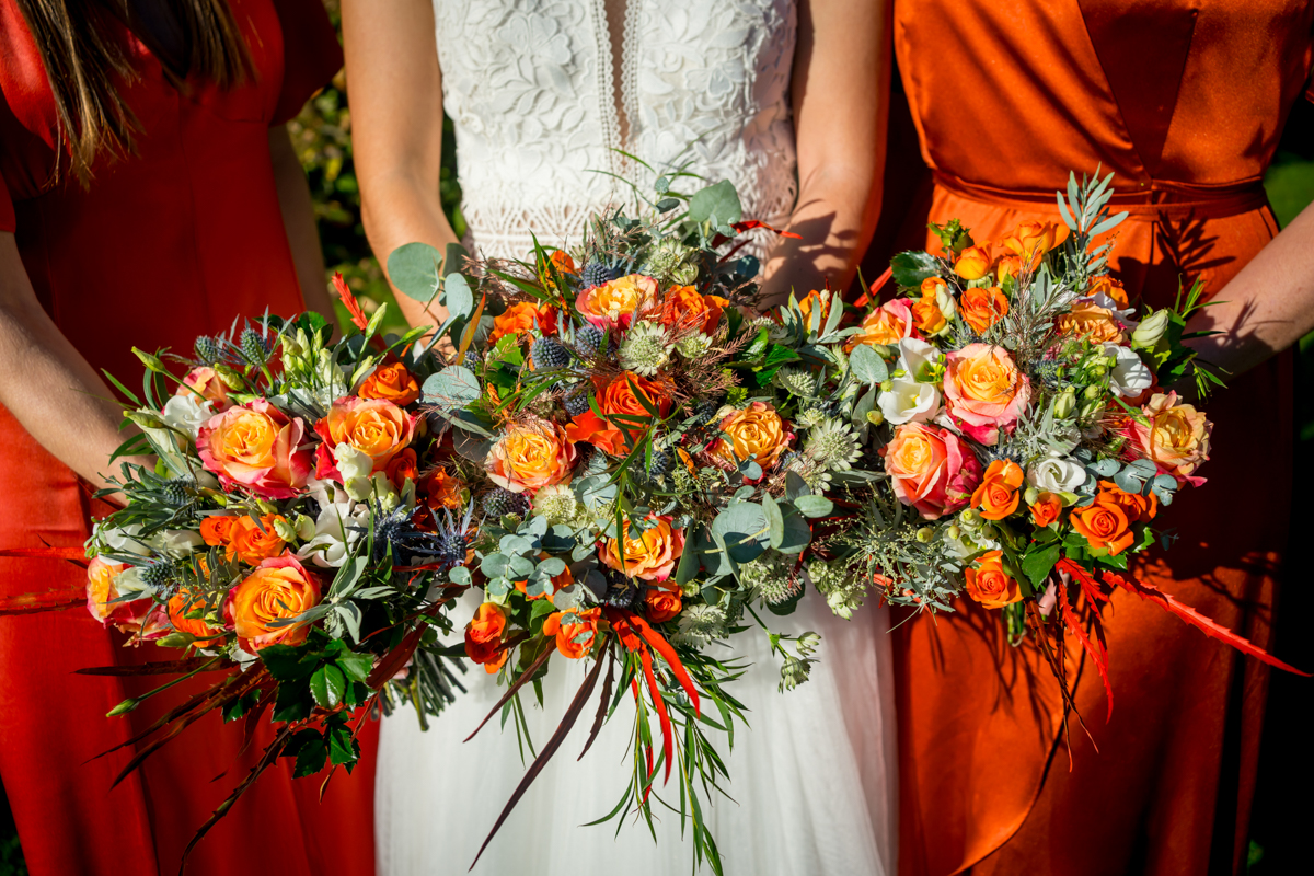 Bride and bridesmaids holding vibrant floral bouquets.