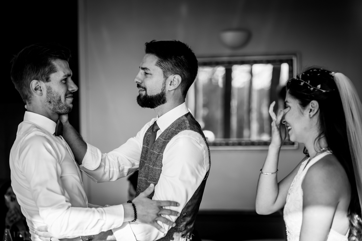 Groom emotional moment with best man and bride.
