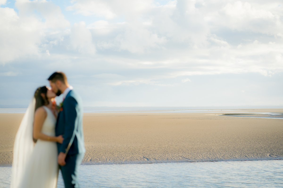 Couple kissing on a sandy beach.