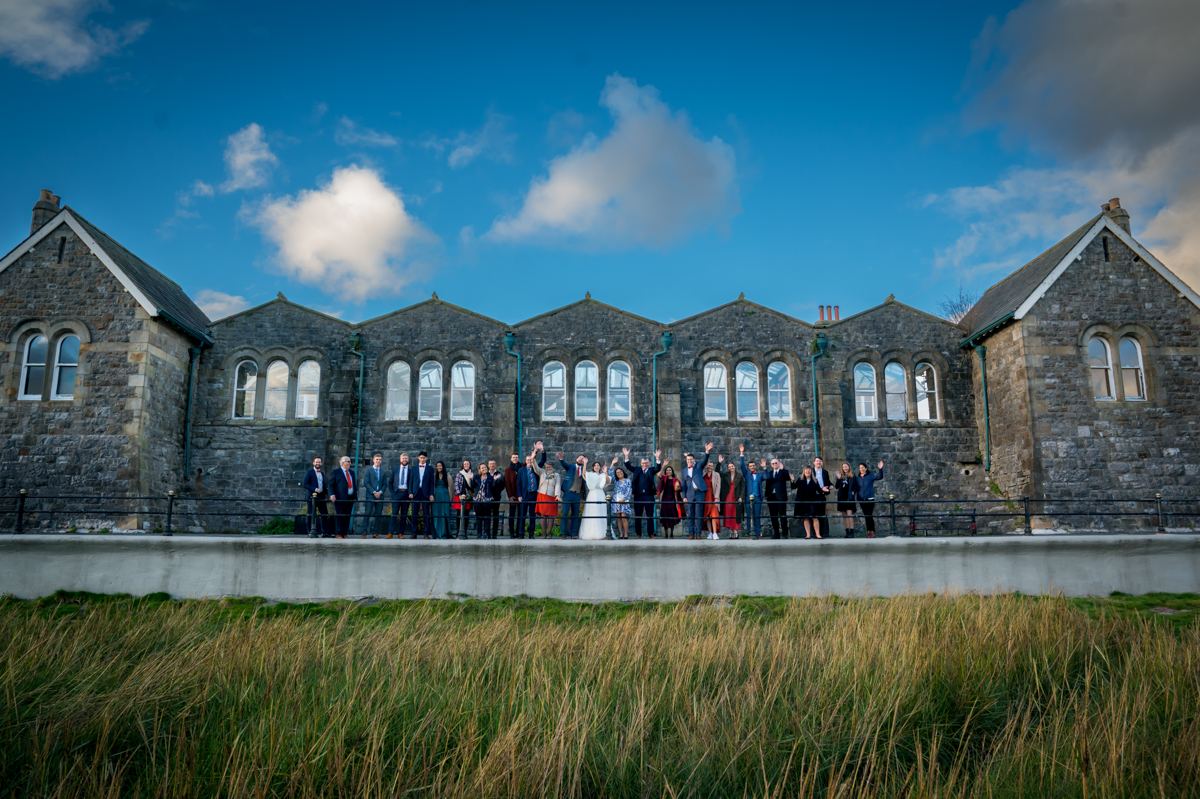 Group outside historic building under blue sky.