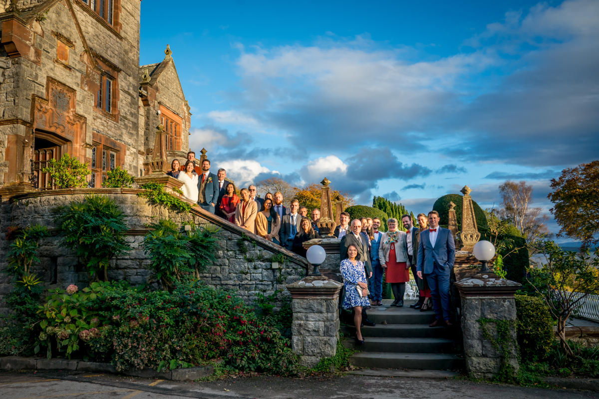 Group photo outside historic stone building with blue sky.