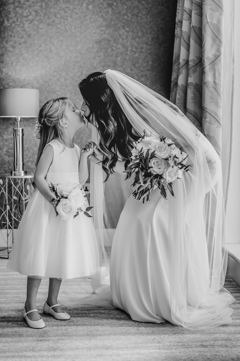 Bride and flower girl share a kiss.