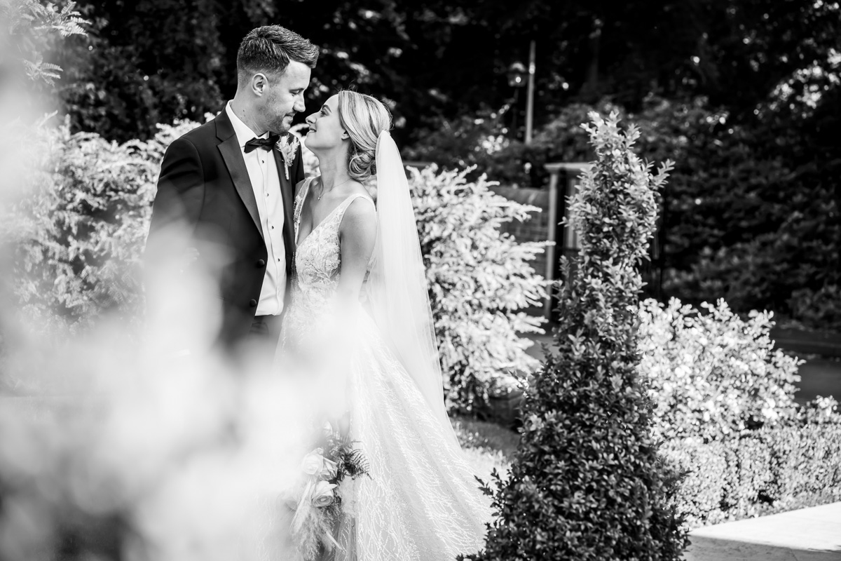 Bride and groom share romantic garden moment.