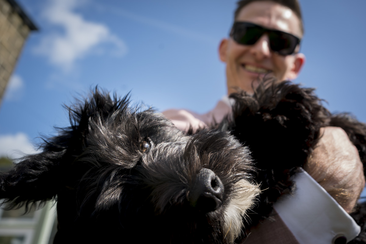 Man holding fluffy black dog outside