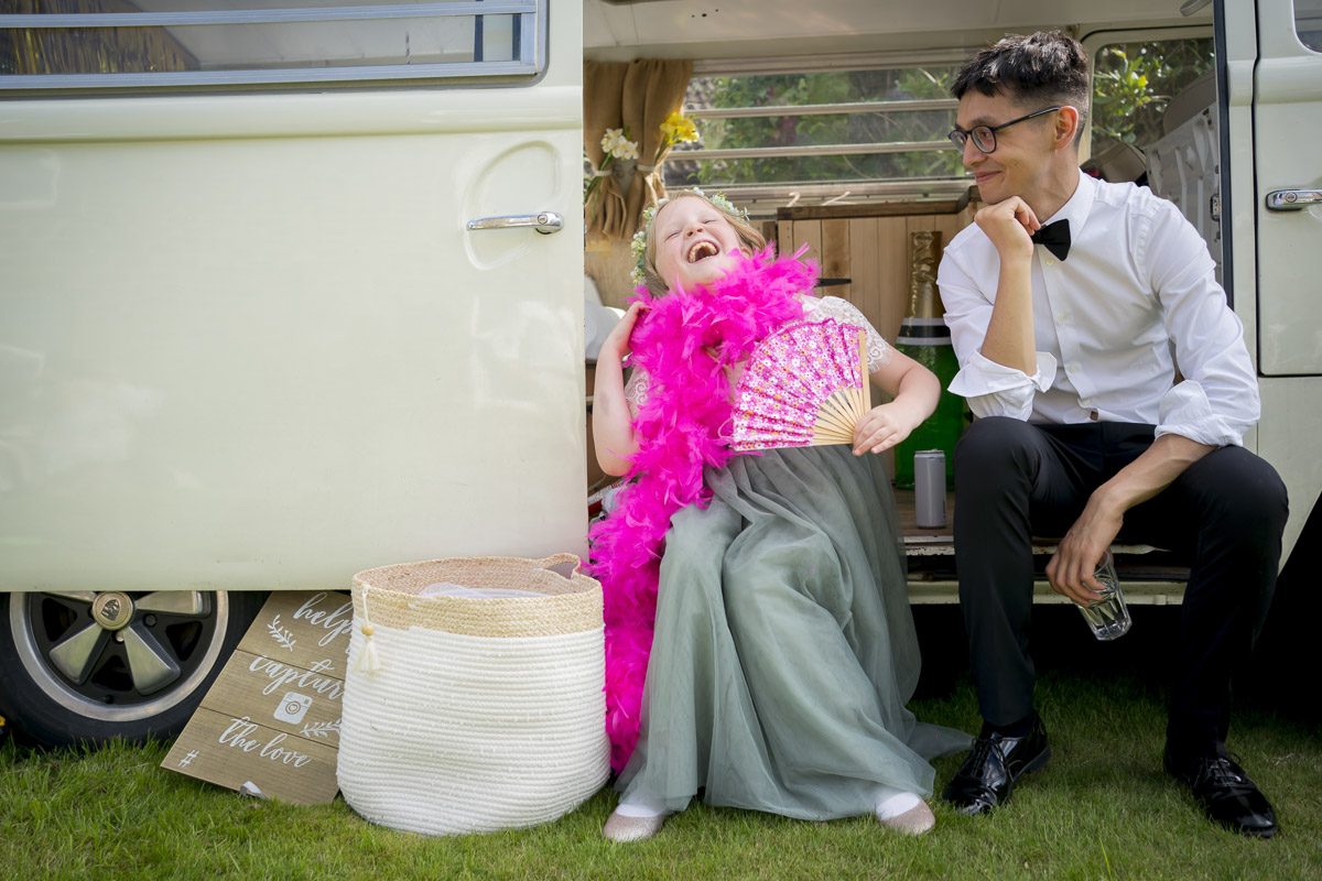 Child laughing with pink boa and fan.