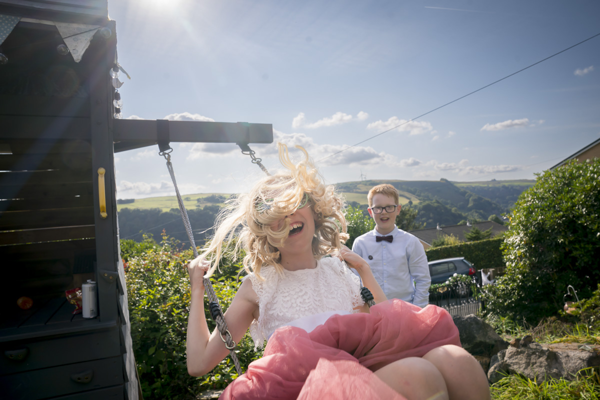 Child swinging joyfully outdoors under sunny sky.