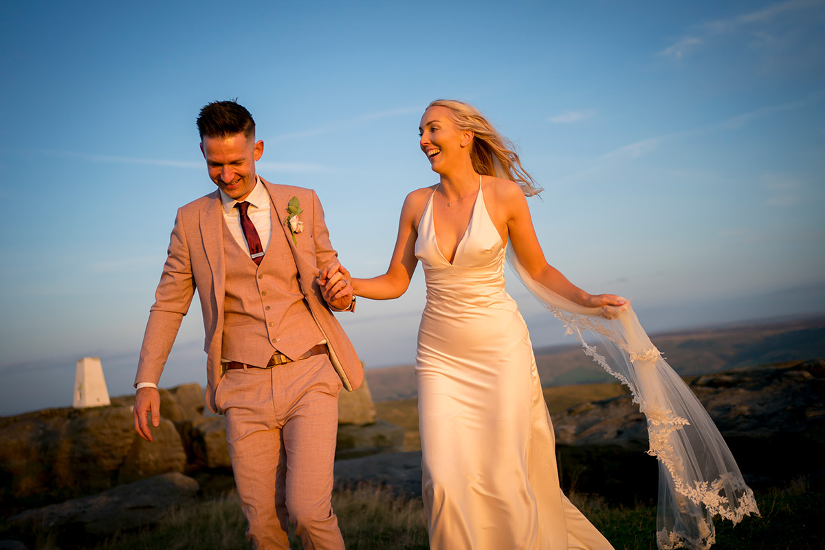 Bride and groom smiling outdoors holding hands.