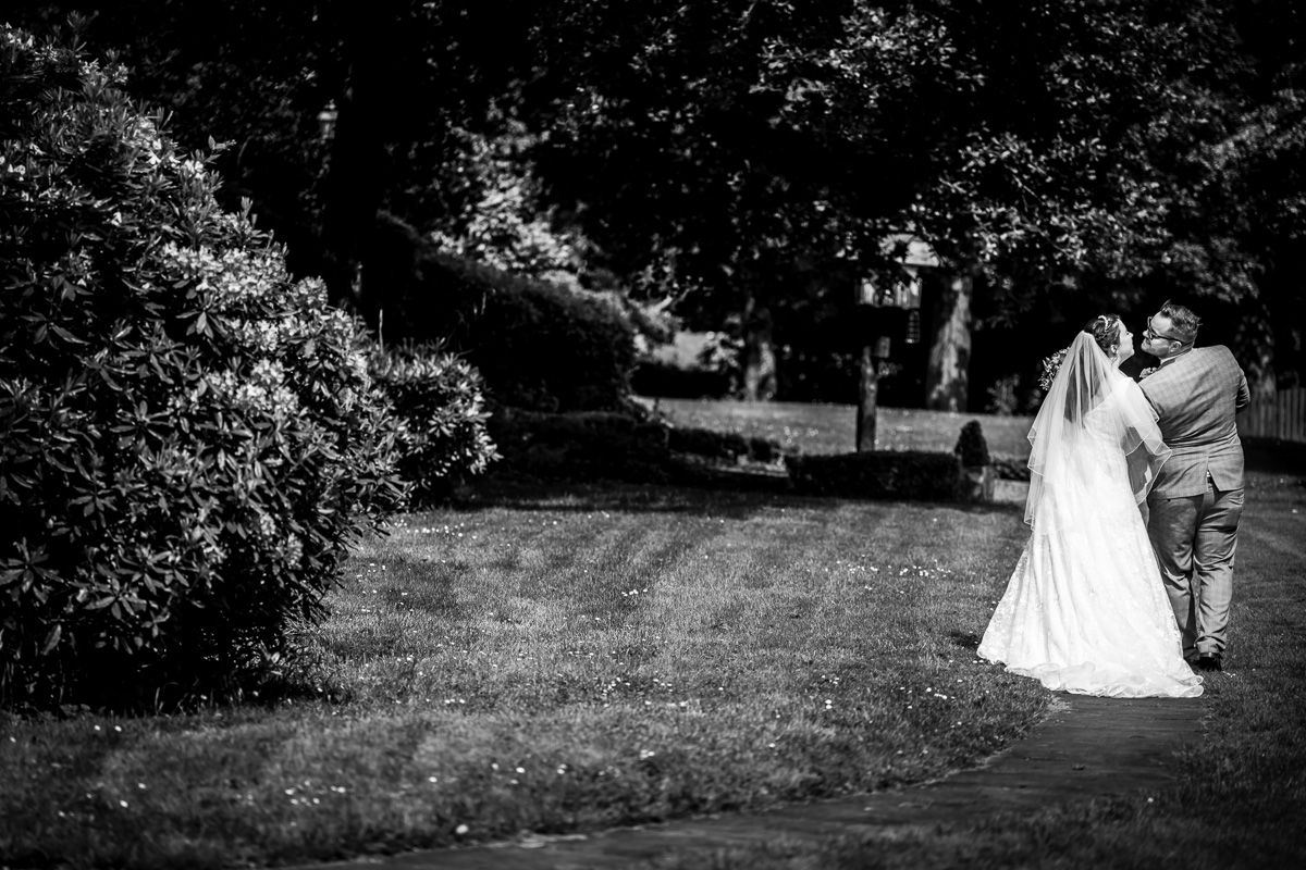 Bride and groom kissing in garden, monochrome photo.