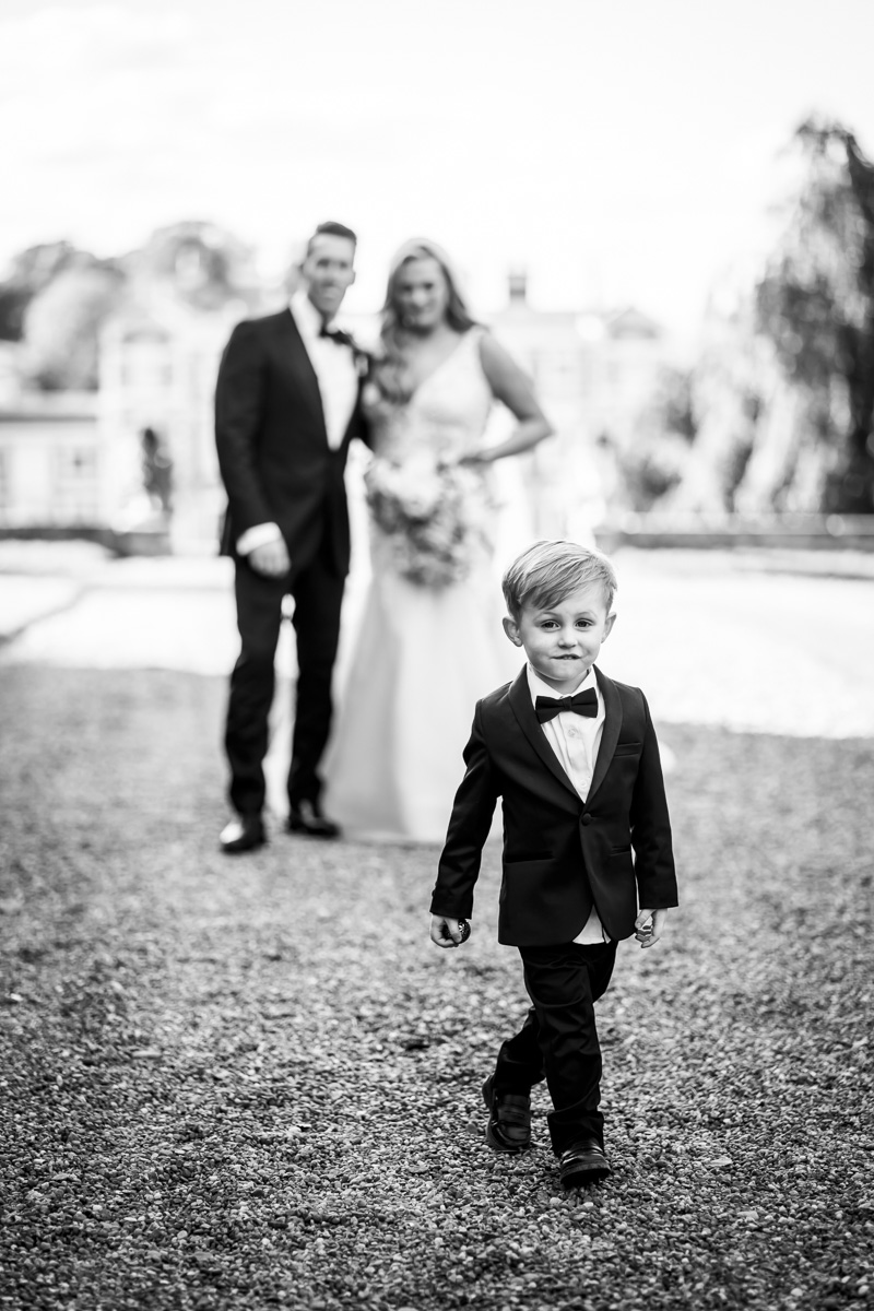 Young boy in suit at wedding, couple in background.
