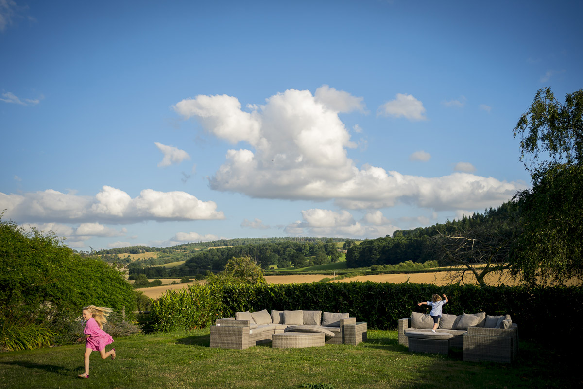 Children playing outdoors with scenic countryside view.