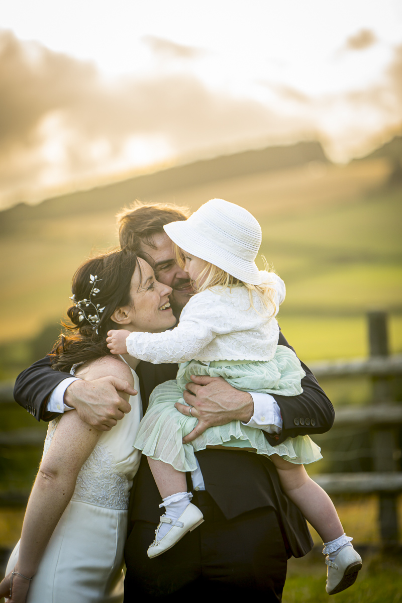 Happy family embracing outdoors in sunset light.