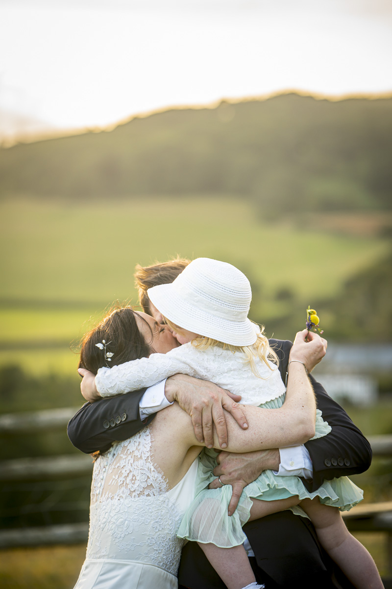 Family hug during outdoor wedding in countryside.