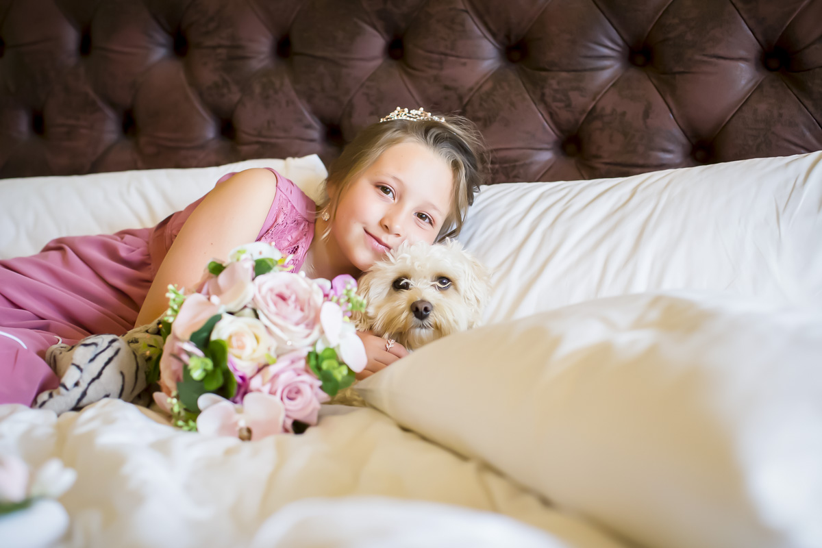 Child with dog and flowers on bed