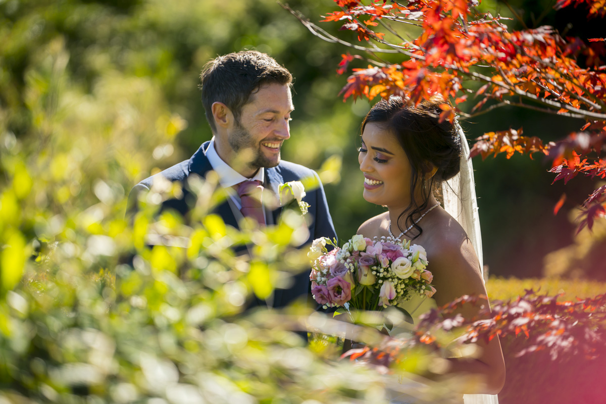 Bride and groom smiling in colourful garden