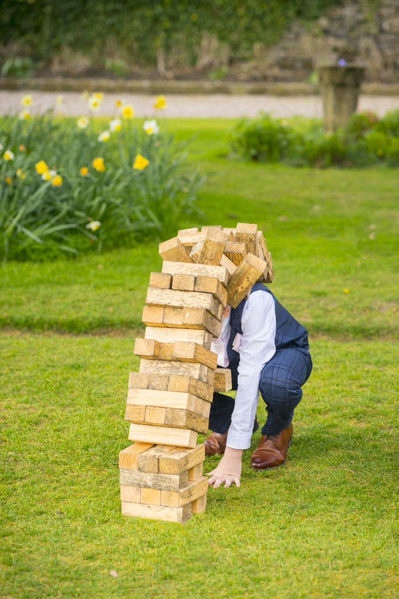 Child playing with giant Jenga blocks on grass.